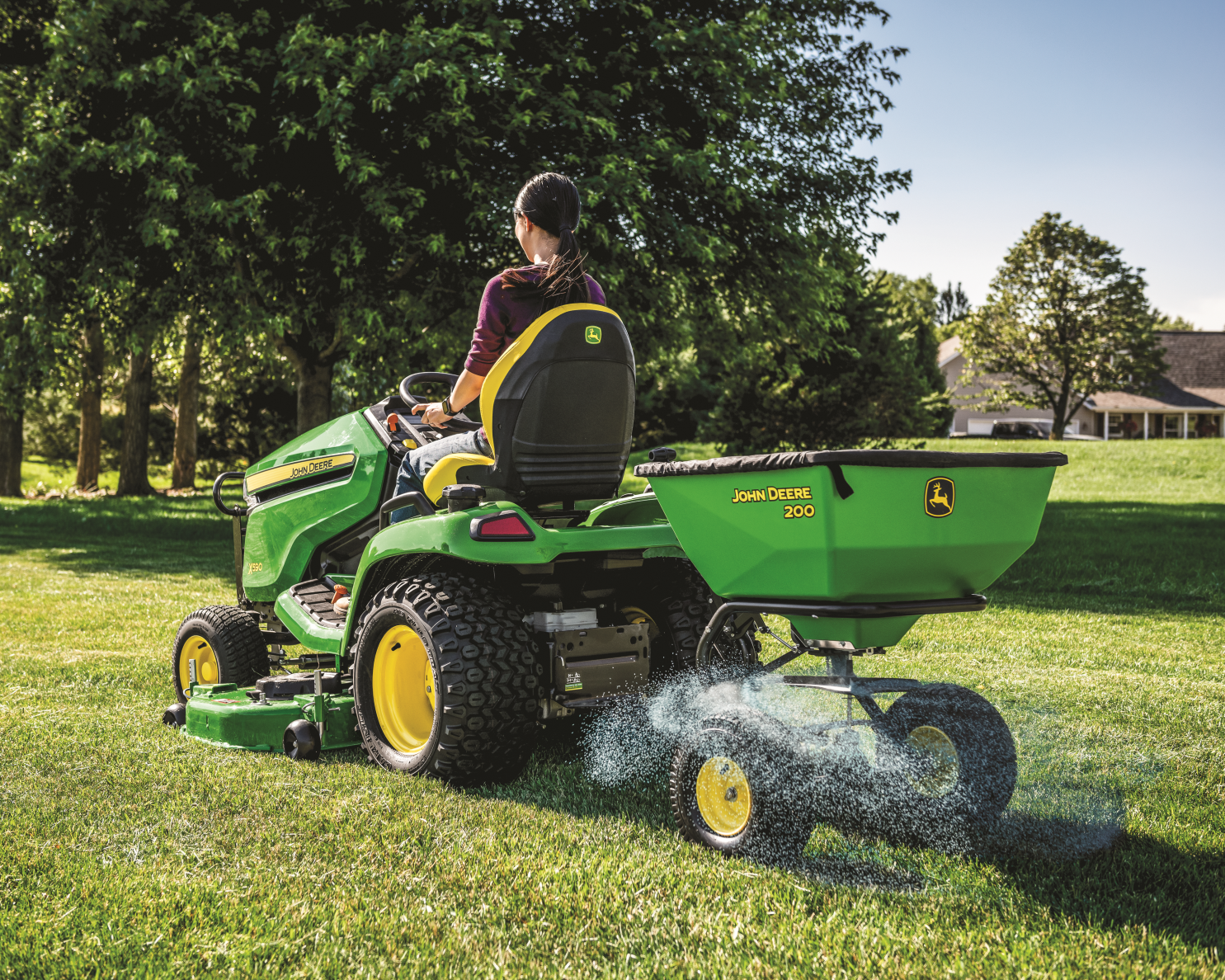 A women is driving a John Deere X590 Select Series Tractor