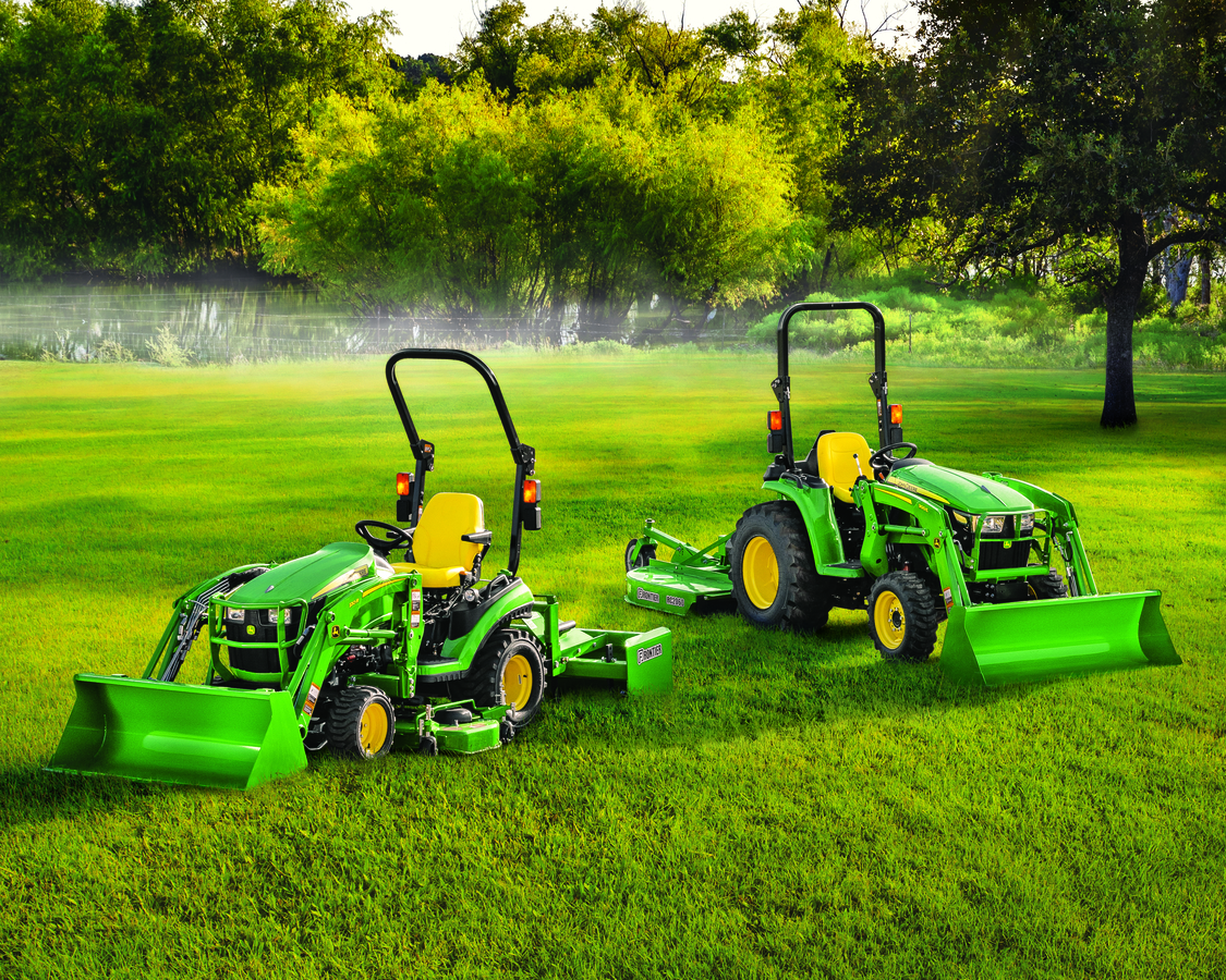Two john deere compact tractors on the green lawn